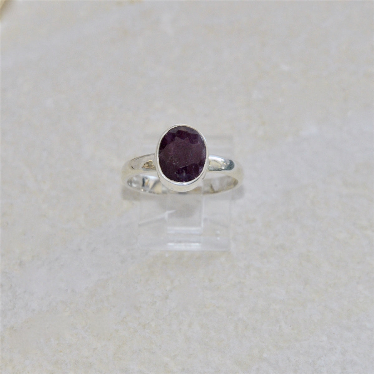 Silver ring with a ruby gemstone on a light beige background